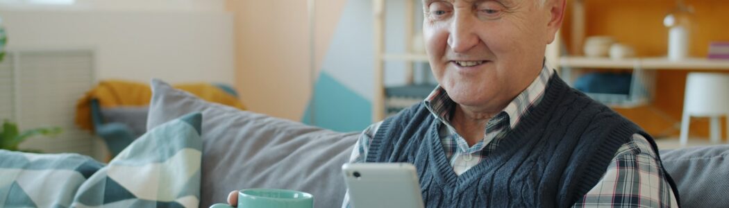 Personne âgée souriante, tenant une tasse et son téléphone